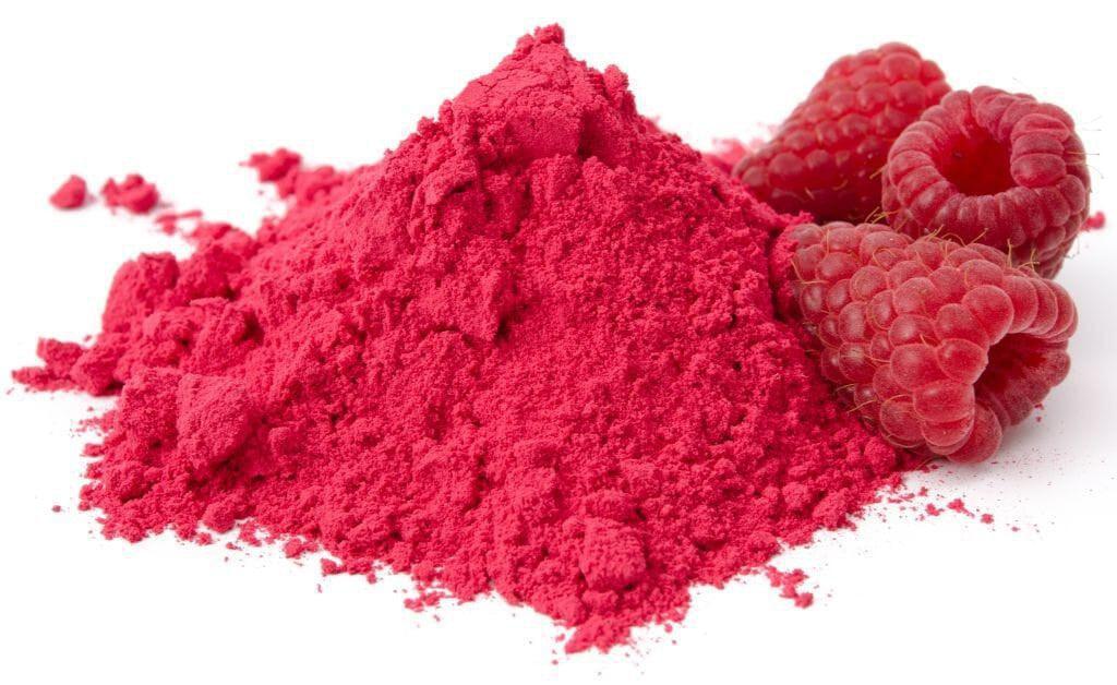 This is a picture of raspberry powder next to fresh raspberries on a white background.