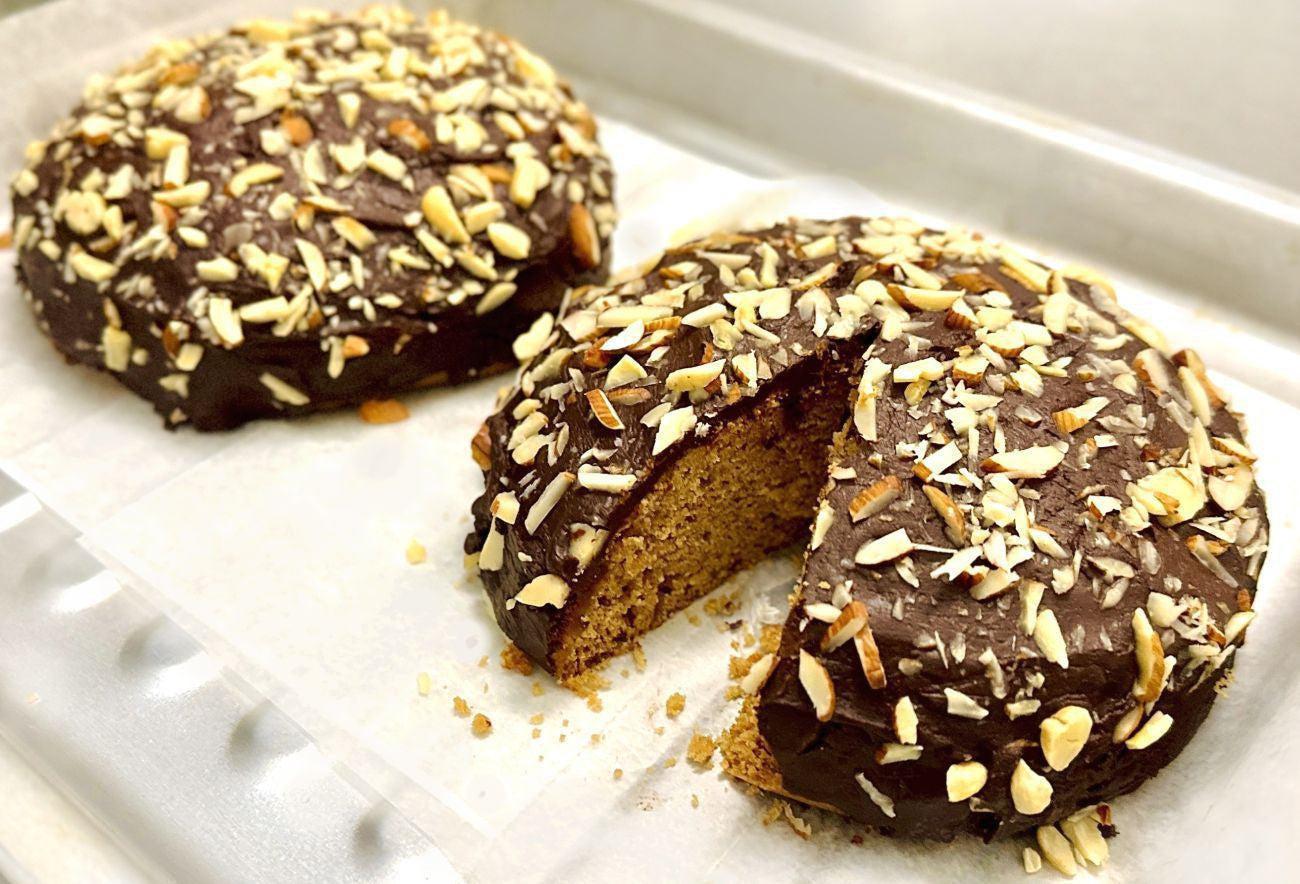 This is a picture of two Chocolate Ganache Orange Cakes (Vegan) on a baking tray, with a piece cut out of one the cakes.