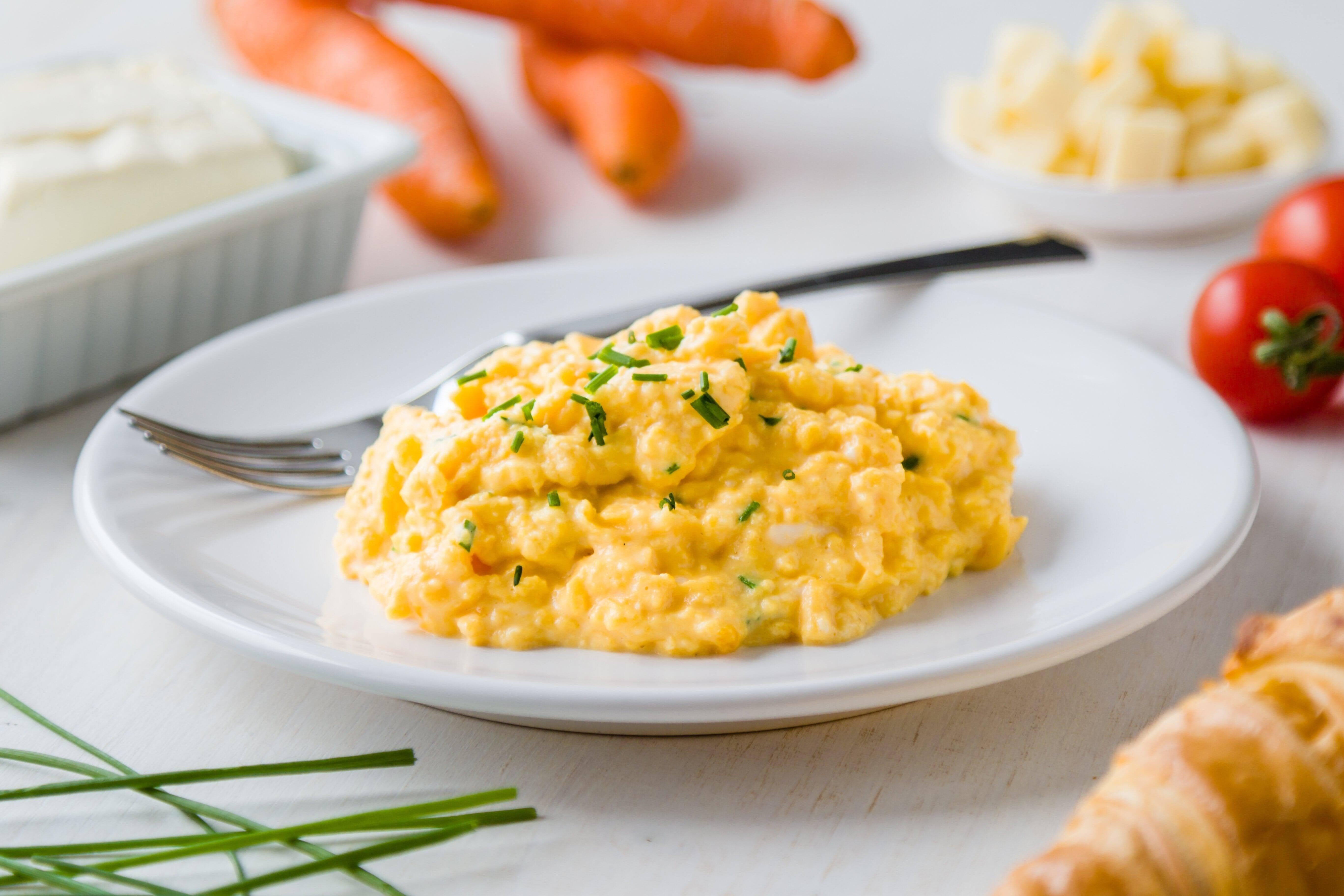 This is a picture of Delicious Scrambled Eggs with Whole Egg Powder on a white plate with a nice table setting in the background.