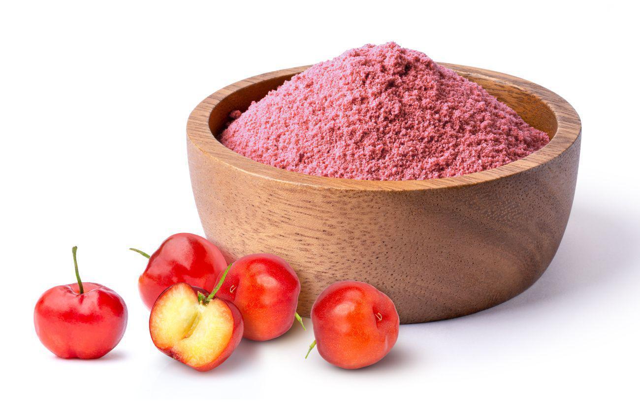 This is a picture of acerola cherries and acerola cherry powder in a wooden bowl on a white background