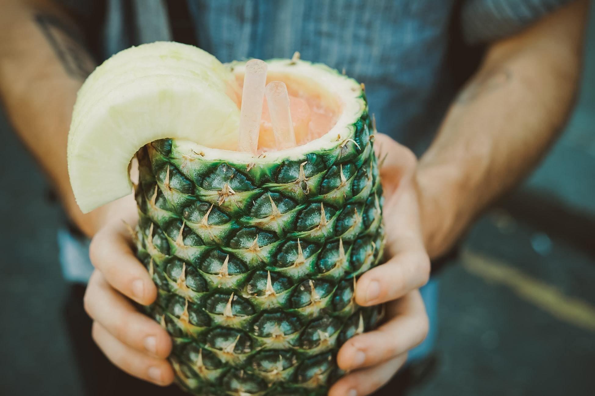 This is a picture of a man holding a Pineapple filled with our Pineapple Protein Superfood Smoothie