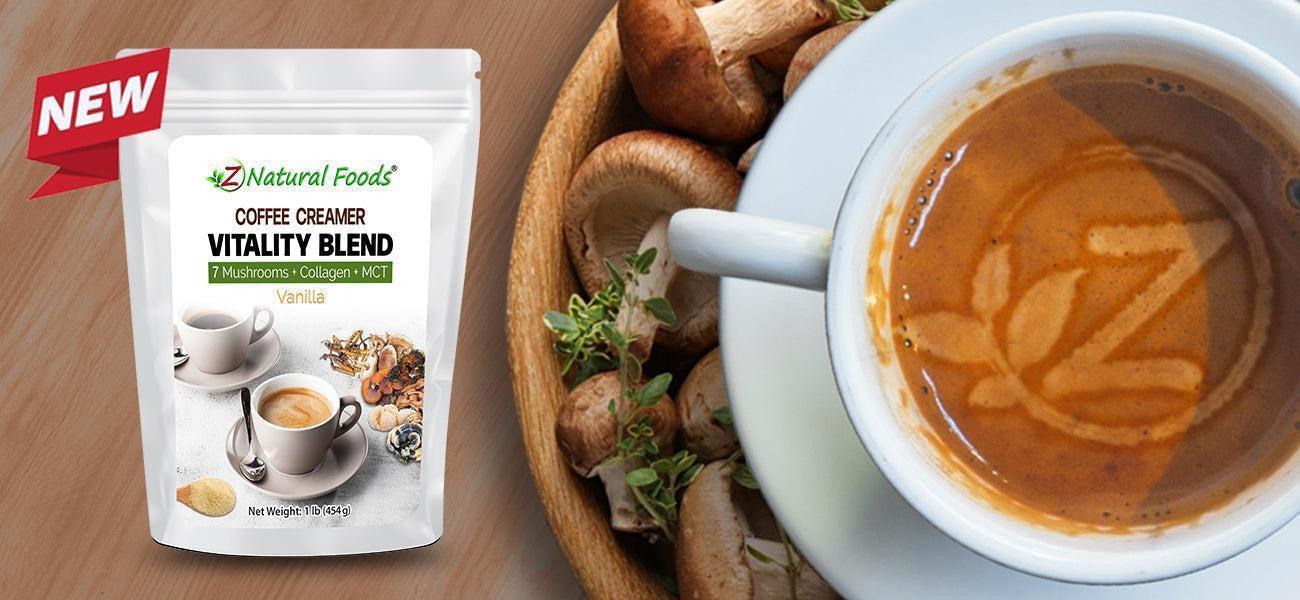 This is a picture of the new Vitality Blend Coffee Creamer net to a big bowl of mushrooms with a coffee cup and a cup of coffee featuring the ZNF logo in it, all on a wooden table