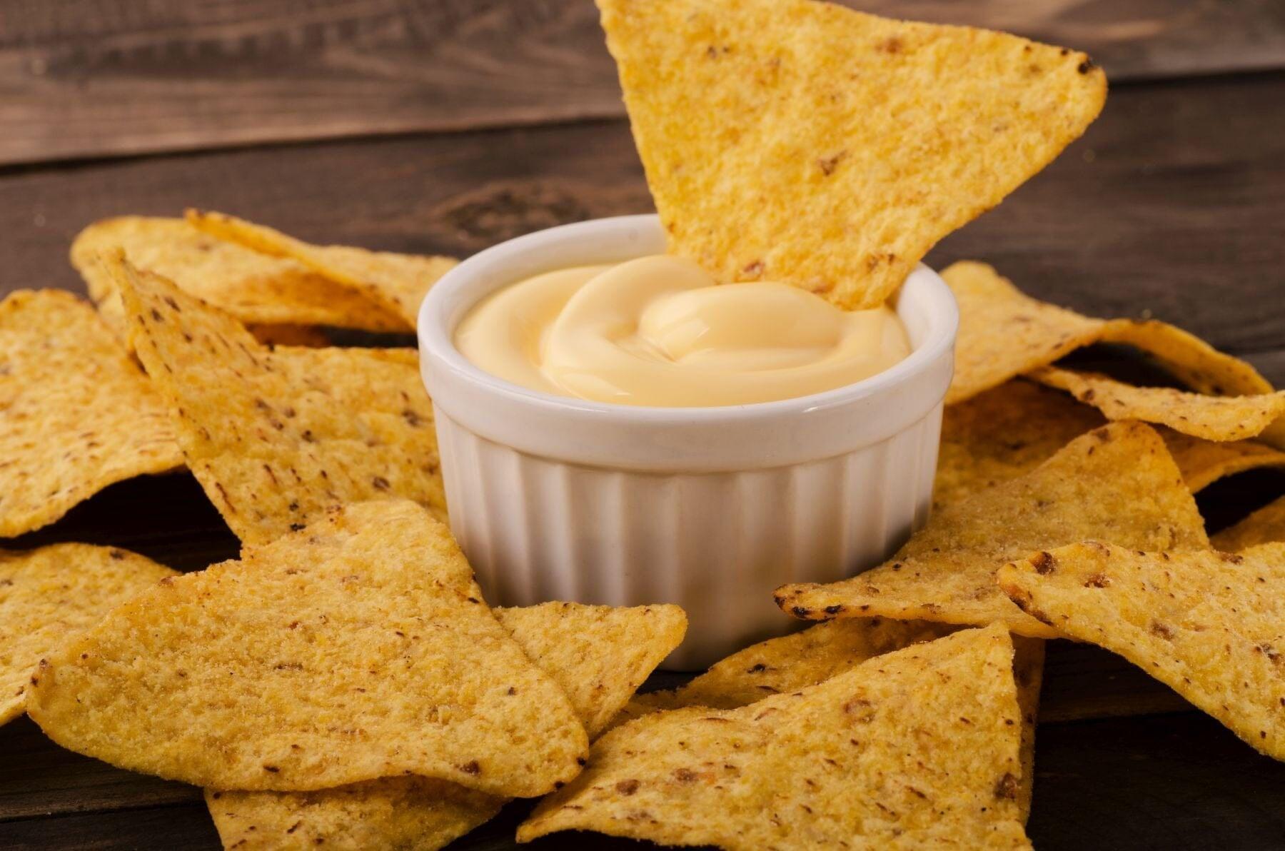 This is a picture of chips and our white cheddar cheese powder dip in a white serving bowl.