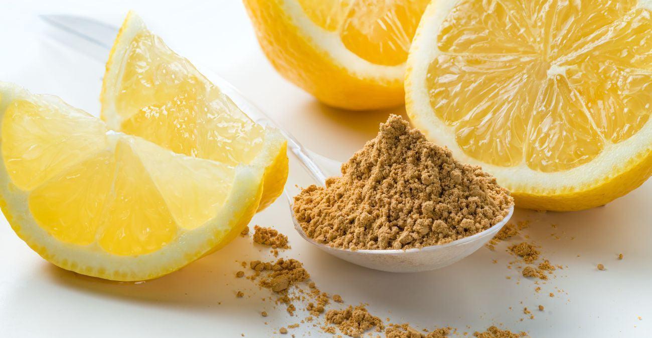 This is a picture of freshly cut lemons and lemon powder on a white bowl, all on a white background.