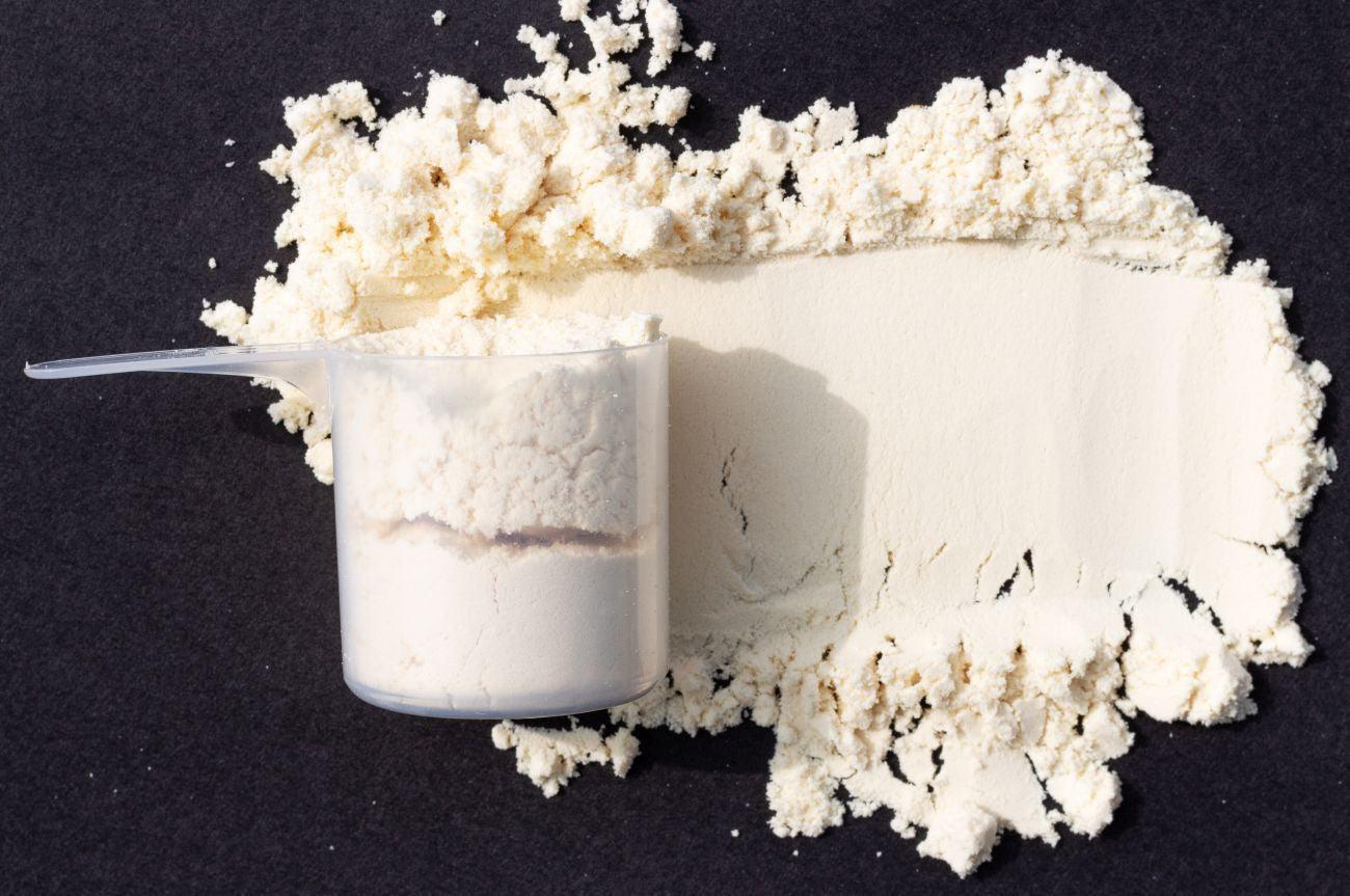 This is a picture of whey protein with a scooper on a black background