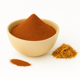 A bowl of reddish-brown catuaba bark powder with bark shavings beside it on a white background.