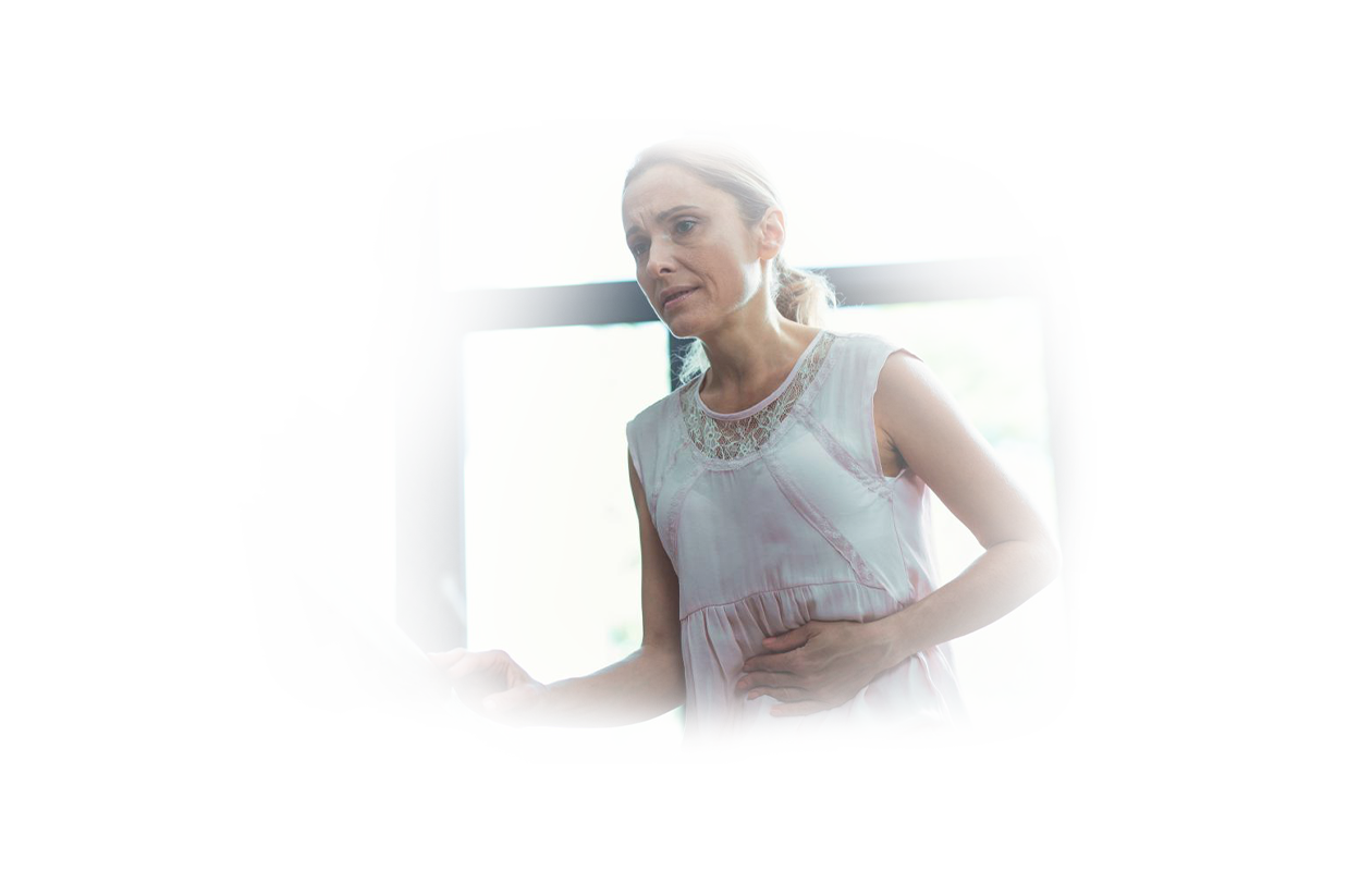 Image of woman suffering from gallstones holding midsection and grimacing.