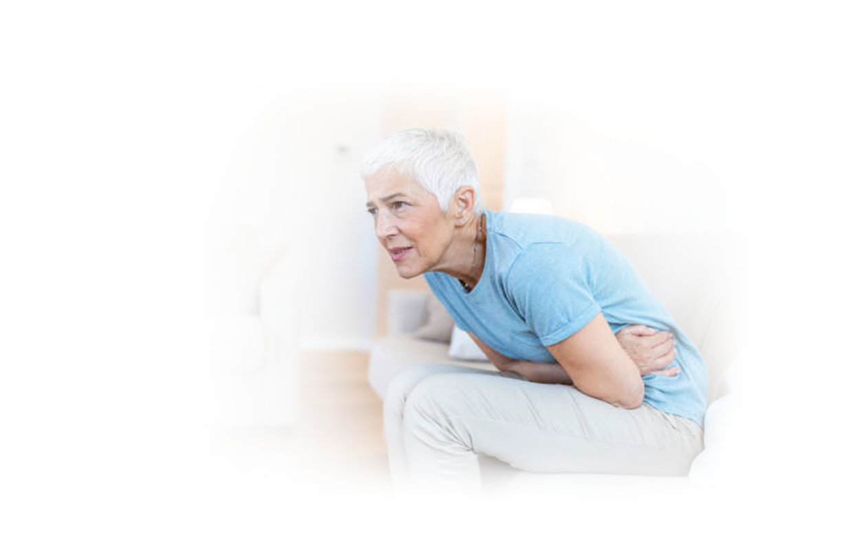 Image of woman doubled over sitting on couch suffering from Gastritis.