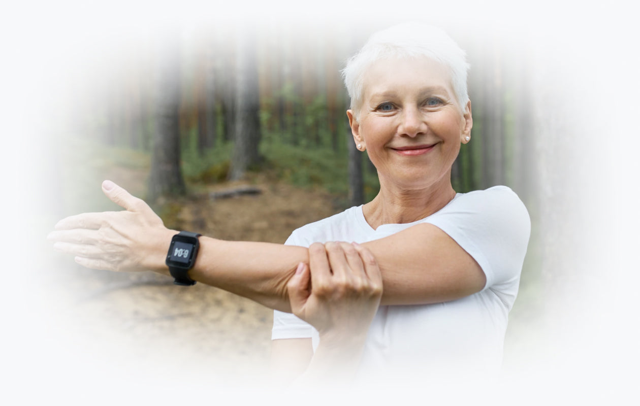 Image of woman in the woods smiling and holding her arm