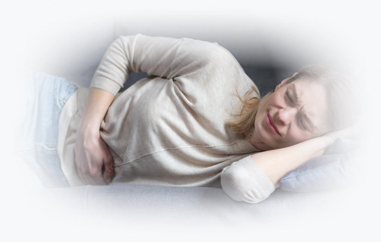 Woman lying down with hand over tummy because of endometriosis pain