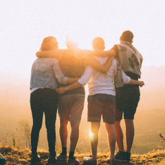 photo from behind of 4 happy friends watching sunset