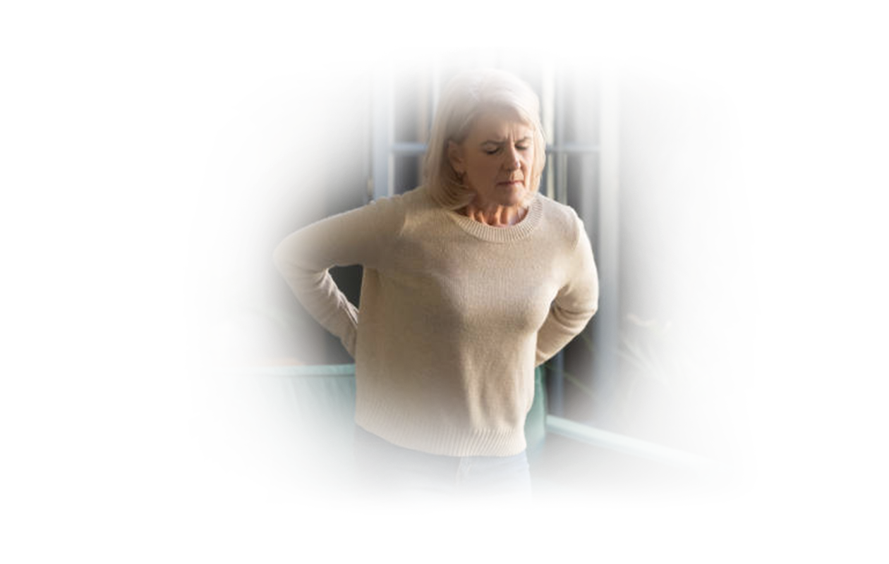 Image of standing woman reaching for back because of fibromyalgia