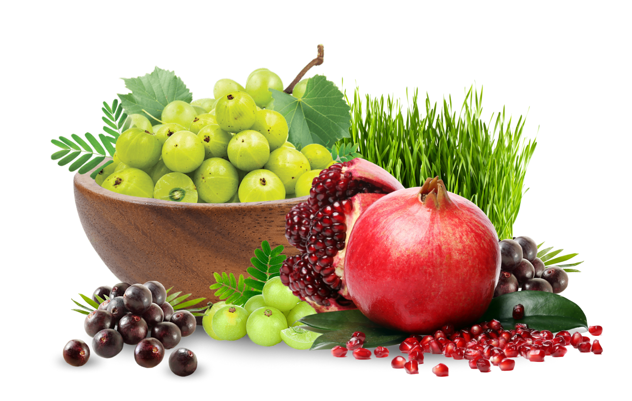 Bowl of Amla fruits alongside sliced pomegranate and wheatgrass.