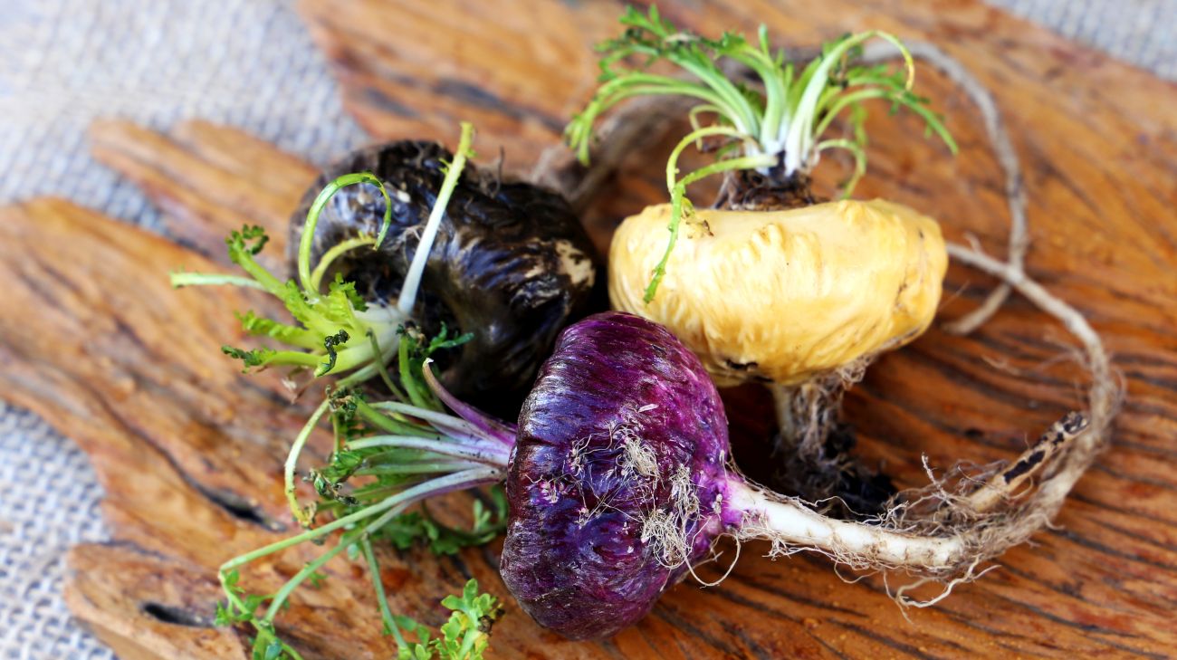 This is a picture of red and yellow maca root on a wooden cutting board.