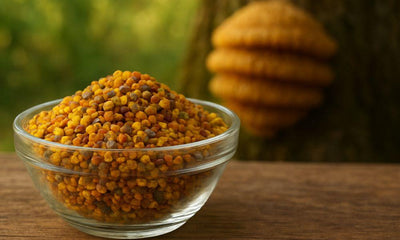 This is a picture of bee pollen in a glass bowl outside on a wooden table with a bee hive on a tree in the background.
