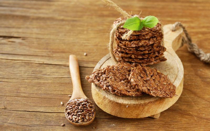 Flax Seed Crackers with Guacamole (Vegan) on a green platter and a white background.