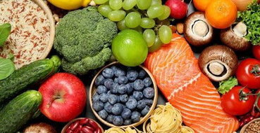 This is a picture of many delicious foods including a salmon filet, a bowl of blueberries, apples, red tomatoes and more