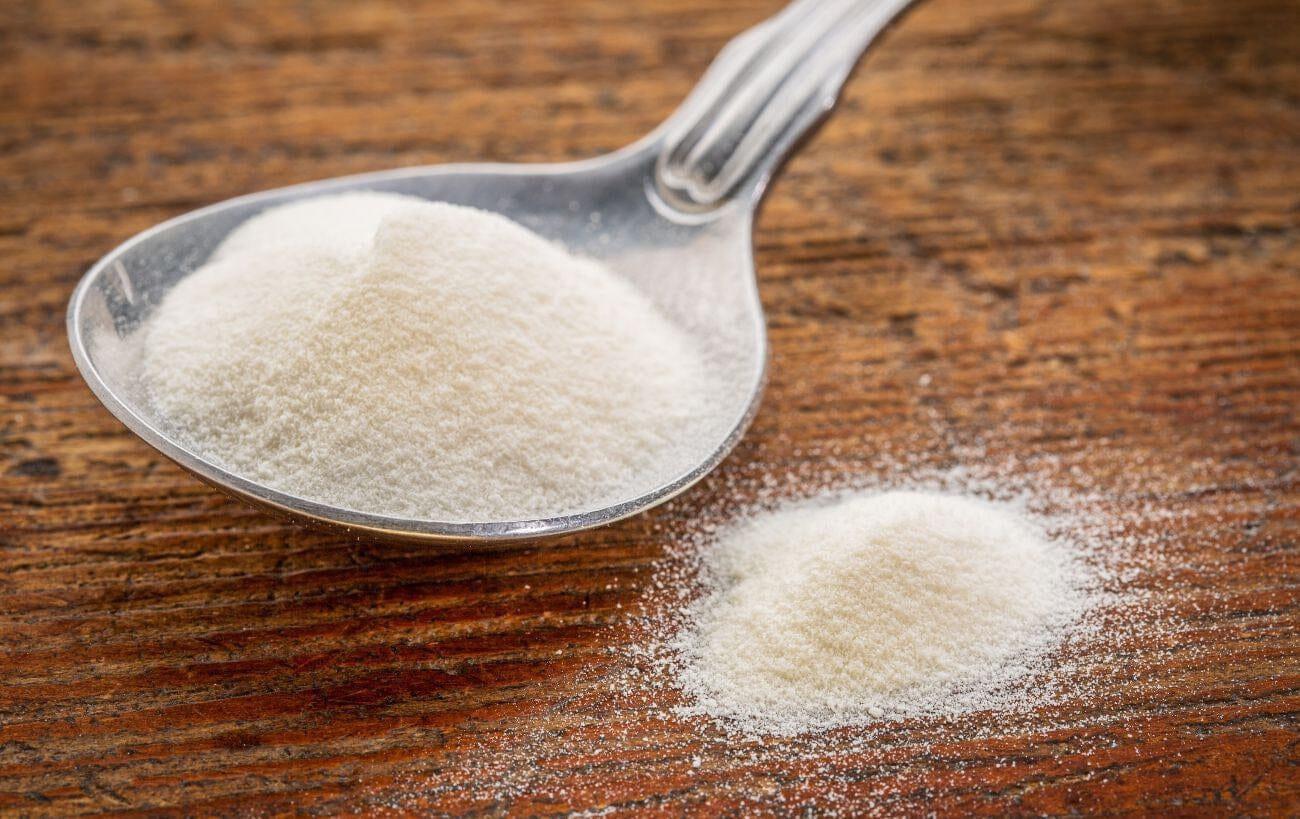 This is a picture of a spoonful of collagen on a wood table