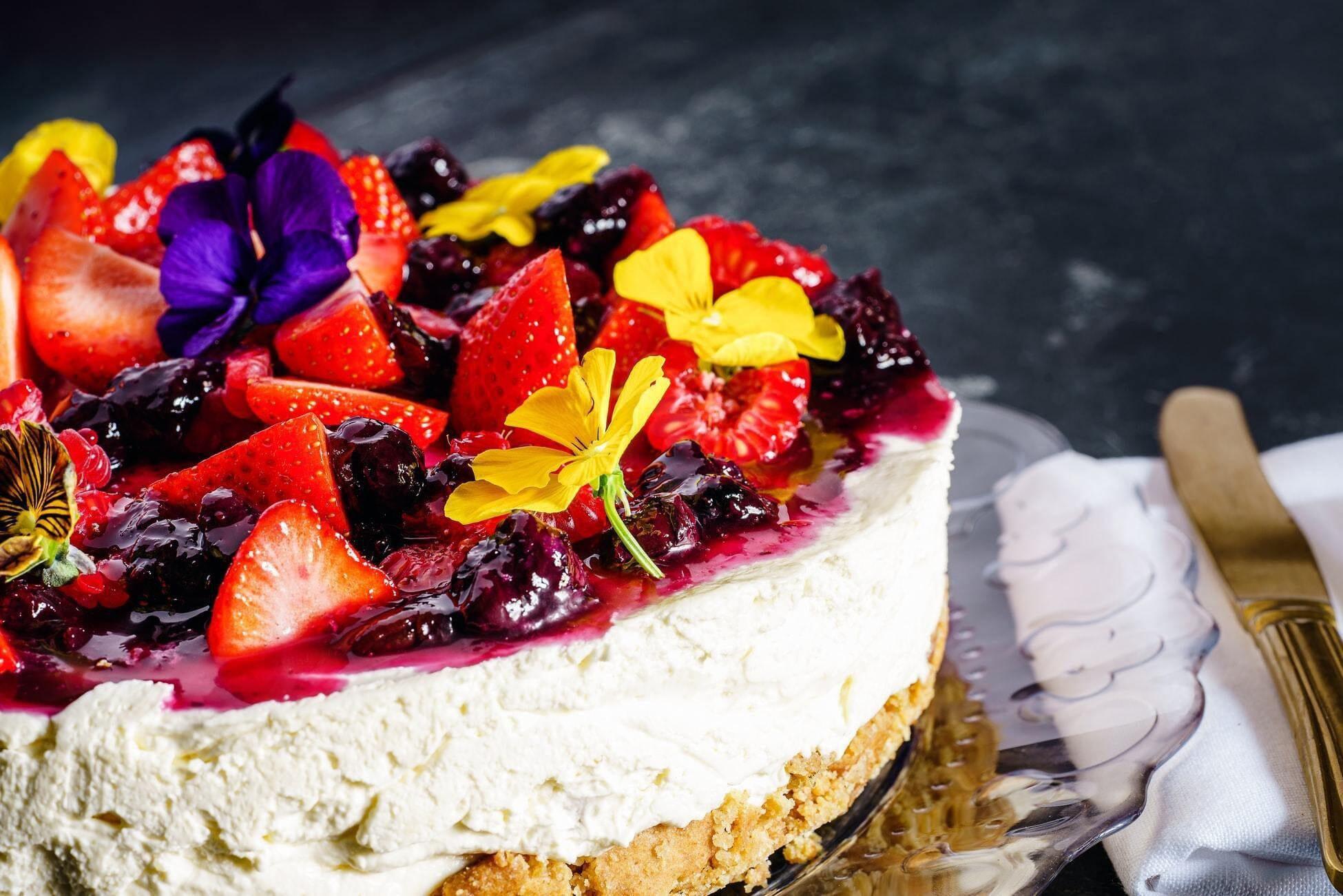 This is a picture of our Vegan Raspberry Cheesecake on a glass platter on a dark colored table.