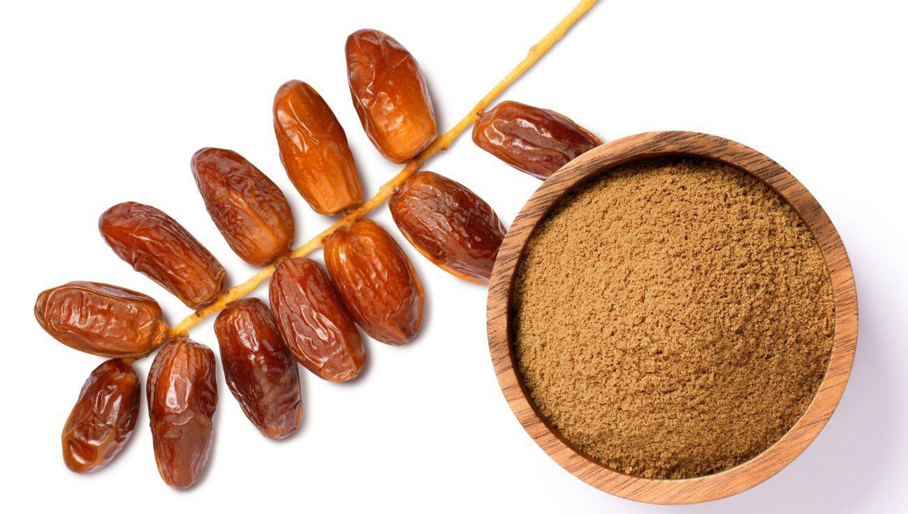 This is a picture of a wooden bowl with date powder, next to a string of dates on a white background.