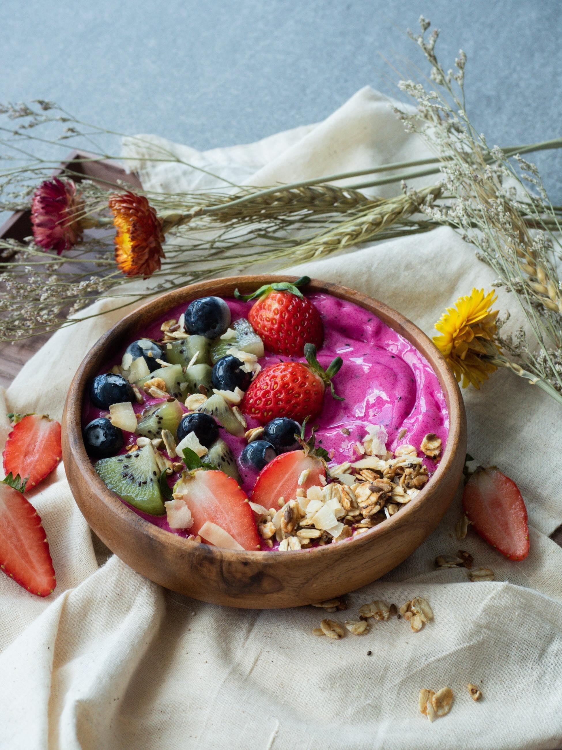 This is a picture of a brown bowl with a berry mix inside on a white tablecloth