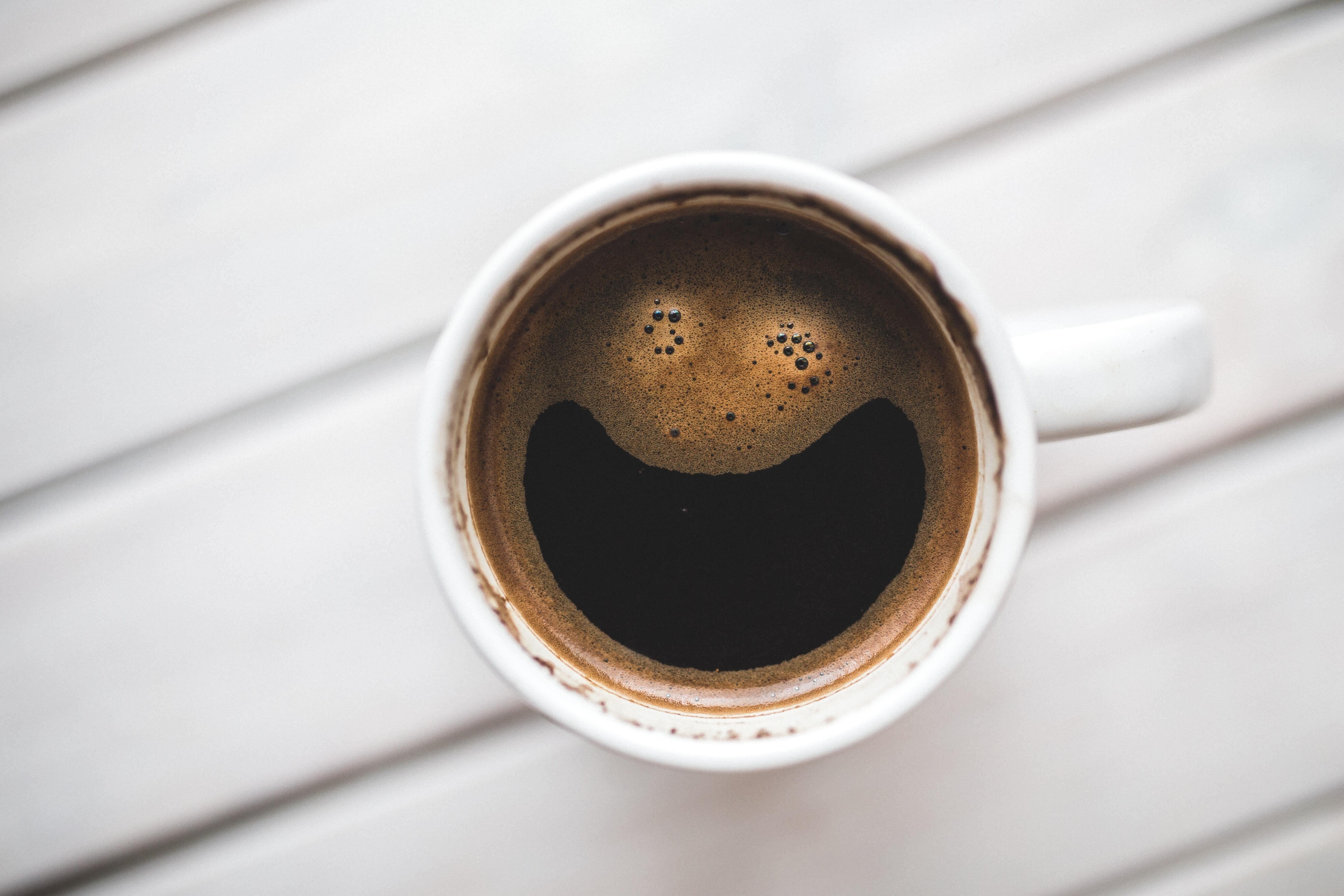 This is a picture of a cup of coffee ion a white mug on a tiled background.