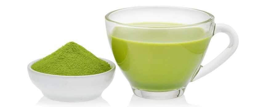 This is a picture of matcha green tea powder and matcha green tea in a glass mug on a white background.