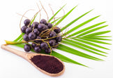 Image of multiple fresh acai berries and green leaves