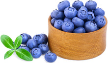 Image of a bunch of fresh Blueberries in a wooden bowl and some outside the bowl and green leaves