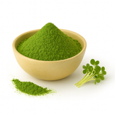 A beige bowl filled with bright green broccoli sprout powder on a white background, with a small pile of powder and fresh sprouts beside it.