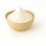 A beige bowl filled with fine white butter powder on a clean white background, with a small amount of powder spilled beside it.