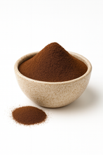 Bowl of organic instant coffee powder with a small pile of powder in front on a white background
