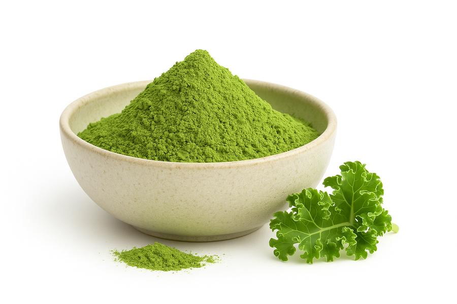 Bowl of organic kale powder with a fresh kale leaf beside it on a white background