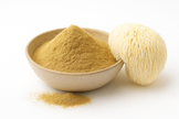 A bowl of organic lion’s mane extract powder with a fresh lion’s mane mushroom on a white background.