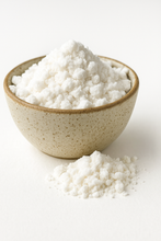 A bowl of organic MCT oil powder with a small pile of powder in front on a white background.
