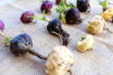 Image of raw whole black, red, and white Maca Root on burlap cloth.