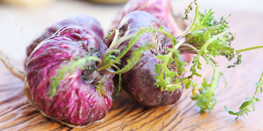 Closeup image of Red Maca Roots on wooden tabletop.