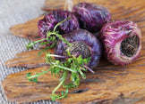 Closeup image of red Maca Roots on wooden cutting board.