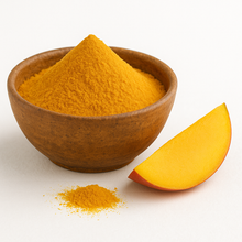 A rustic brown ceramic bowl filled with organic mango powder, with a small pile of powder in front and a fresh mango slice beside it on a white background.