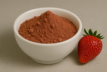 Faded red powder blended with seeds in a white bowl next to a whole strawberry.