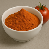 Red powder inside a white bowl next to a tomato.