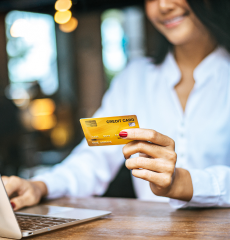 Image of a woman holding a credit card while browsing on a laptop